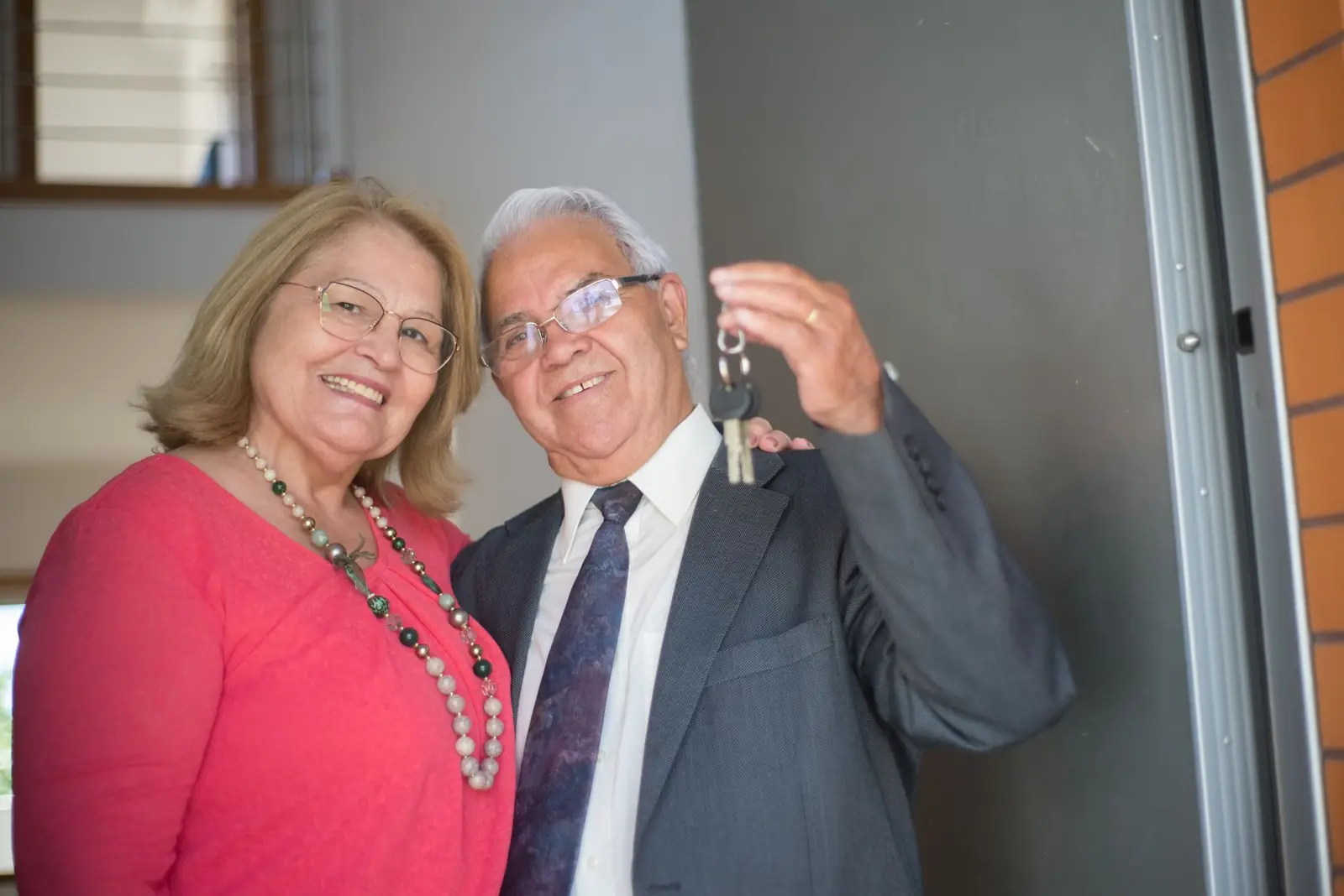 Casal de idosos sorrindo segurando as chaves de casa